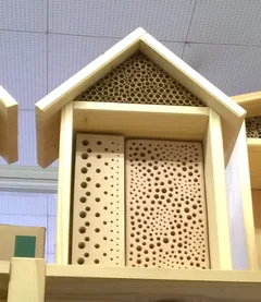 A wild bee nesting aid with holes of different diameters and bundles of hollow plant stems.